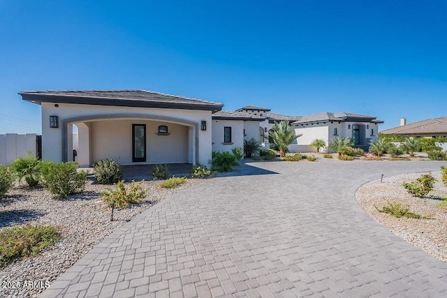 prairie-style home with fence, curved driveway, and stucco siding