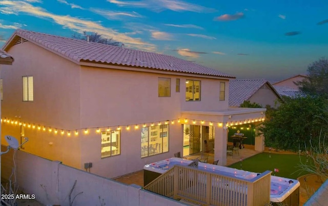 29228 N 48th St, Cave Creek, AZ 85331 - back of property at dusk featuring a hot tub, a tiled roof, a patio area, and stucco siding