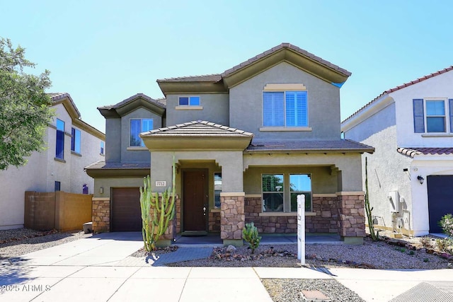 7712 S 37th Way, Phoenix, AZ 85042 - view of front of house featuring stone siding, an attached garage, covered porch, stucco siding, and driveway