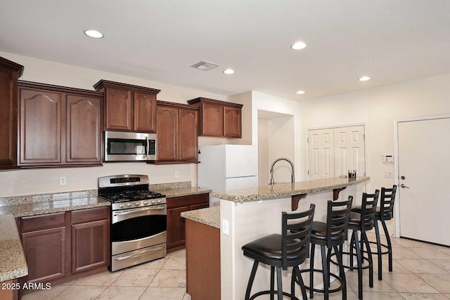 7712 S 37th Way, Phoenix, AZ 85042 - kitchen featuring appliances with stainless steel finishes, a kitchen island with sink, light stone counters, recessed lighting, and light tile patterned floors