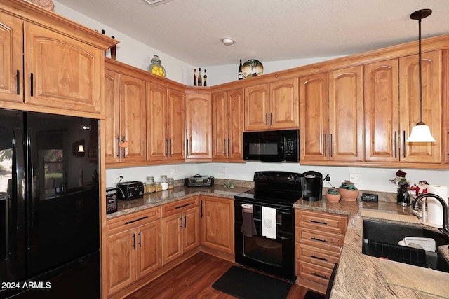 kitchen with light stone countertops, sink, decorative light fixtures, and black appliances