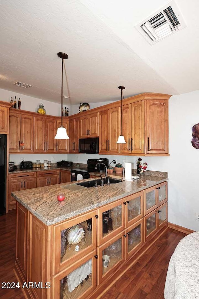 kitchen featuring stone counters, black appliances, sink, dark hardwood / wood-style floors, and decorative light fixtures