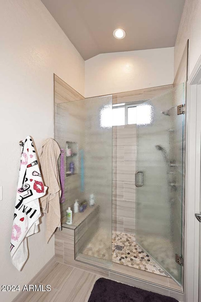 bathroom with a shower with door and lofted ceiling