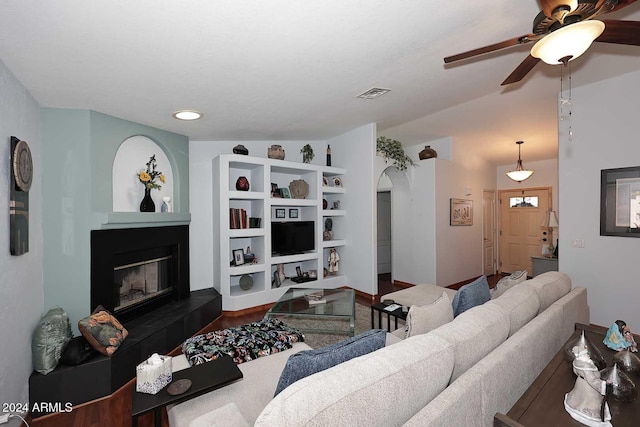 living room with hardwood / wood-style floors, ceiling fan, built in shelves, and vaulted ceiling