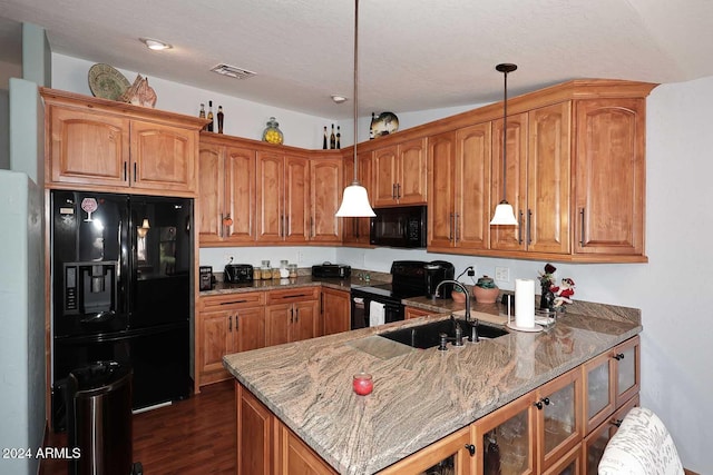 kitchen with stone counters, sink, dark wood-type flooring, hanging light fixtures, and black appliances