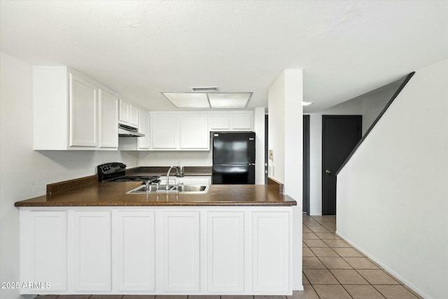 kitchen with dark countertops, freestanding refrigerator, a peninsula, under cabinet range hood, and a sink