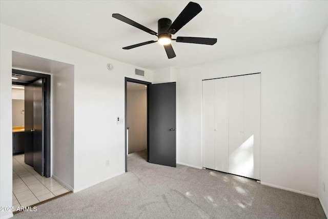 unfurnished bedroom featuring light carpet, a closet, visible vents, and a ceiling fan