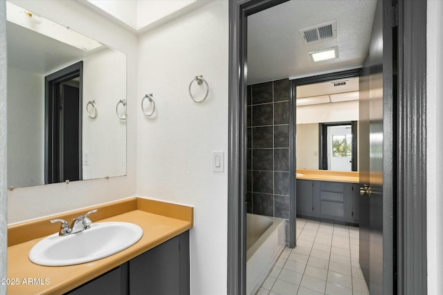 bathroom with visible vents, vanity, a textured ceiling, and tile patterned floors