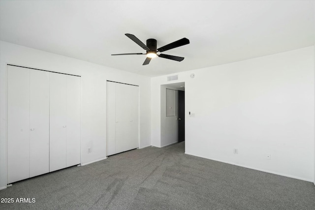 unfurnished bedroom featuring a ceiling fan, carpet, visible vents, and two closets