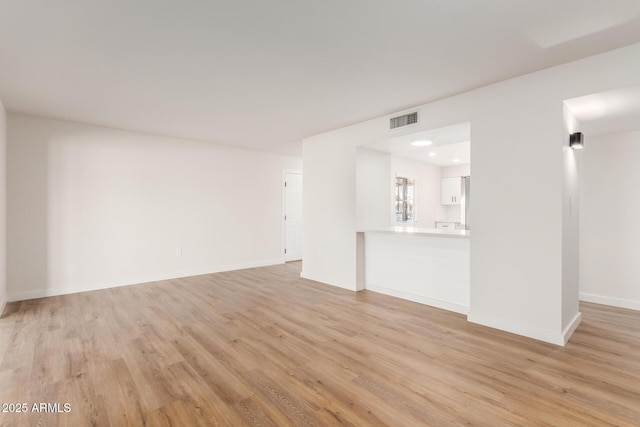 10750 W Abbott Ave, Sun City, AZ 85351 - unfurnished living room with light wood finished floors, visible vents, and baseboards