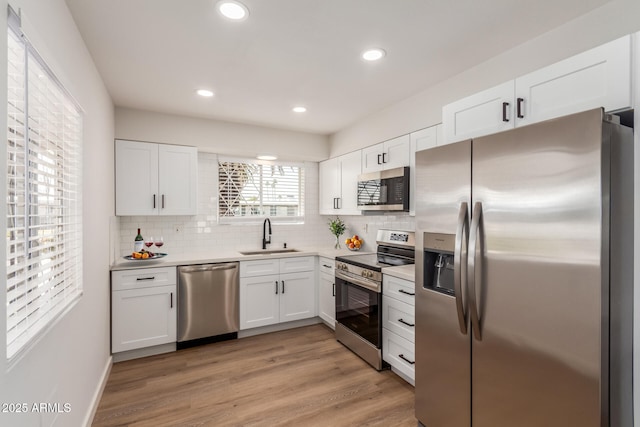 10750 W Abbott Ave, Sun City, AZ 85351 - kitchen with stainless steel appliances, backsplash, light wood-style floors, white cabinets, and a sink