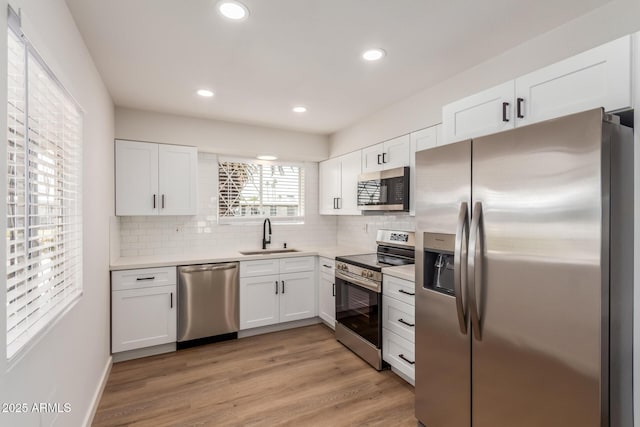 10750 W Abbott Ave, Sun City, AZ 85351 - kitchen with stainless steel appliances, tasteful backsplash, white cabinets, a sink, and light wood-type flooring