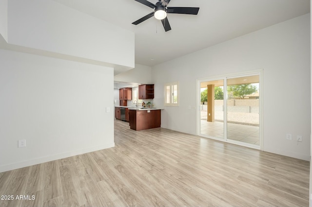 unfurnished living room with sink, high vaulted ceiling, ceiling fan, and light wood-type flooring