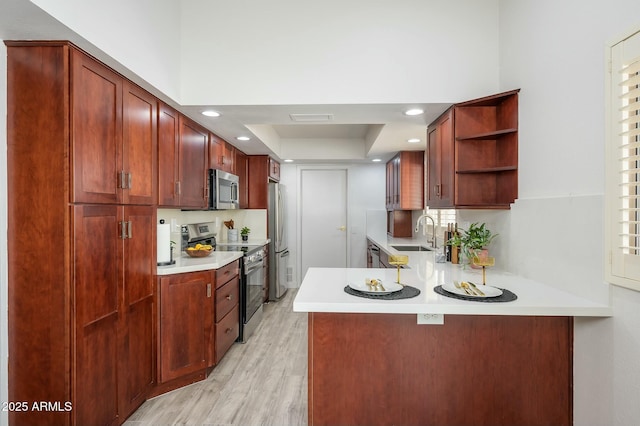 kitchen featuring appliances with stainless steel finishes, sink, light hardwood / wood-style flooring, and kitchen peninsula