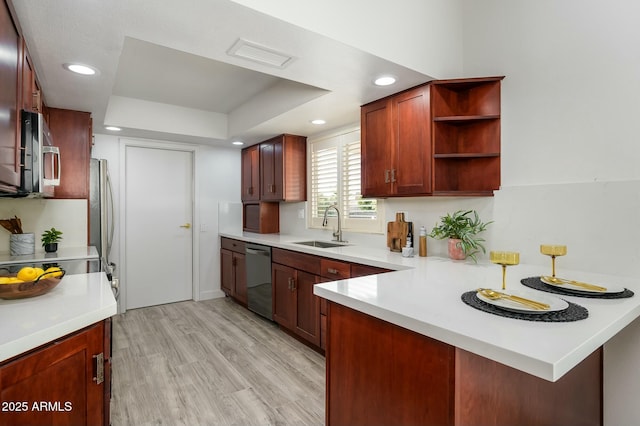 kitchen with appliances with stainless steel finishes, sink, light hardwood / wood-style floors, kitchen peninsula, and a raised ceiling