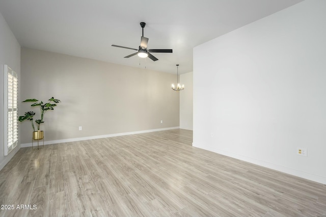 spare room featuring ceiling fan with notable chandelier and light hardwood / wood-style flooring