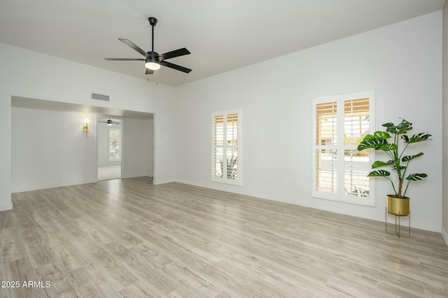 empty room with ceiling fan, a healthy amount of sunlight, and light wood-type flooring