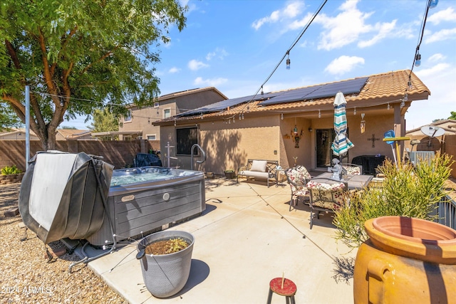 back of house with outdoor lounge area, solar panels, a patio, and a hot tub