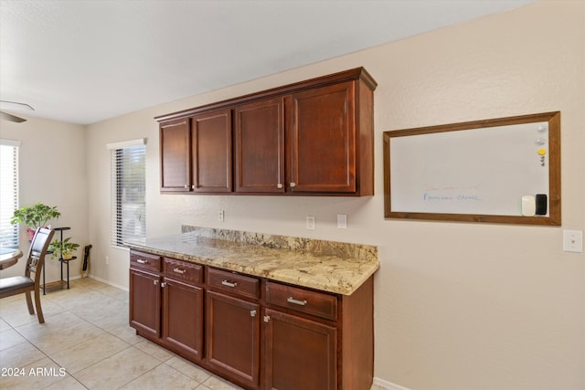 kitchen with light stone countertops, ceiling fan, and light tile patterned floors