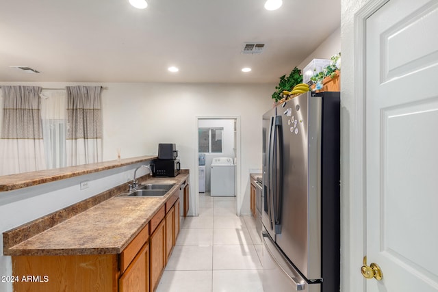 kitchen with sink, light tile patterned floors, stainless steel fridge with ice dispenser, and separate washer and dryer