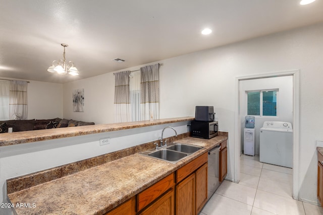 kitchen featuring light tile patterned floors, an inviting chandelier, stainless steel appliances, washing machine and dryer, and sink