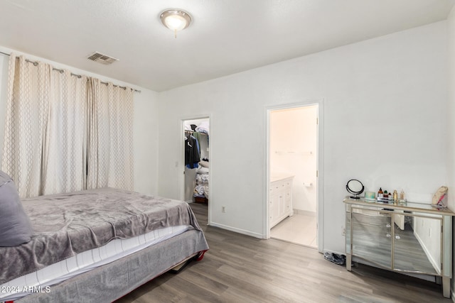 bedroom featuring a closet, a spacious closet, hardwood / wood-style flooring, and connected bathroom