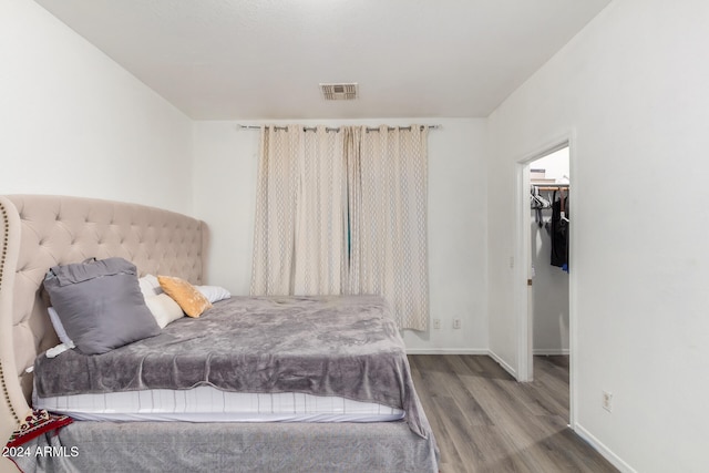 bedroom with a spacious closet and hardwood / wood-style floors