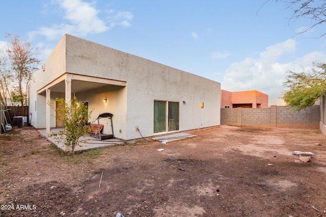 back house at dusk with a patio area and central AC unit