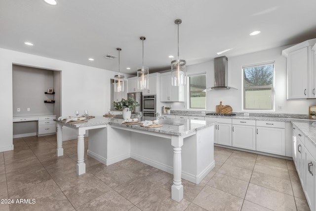 kitchen with white cabinets, a kitchen island, a kitchen bar, and wall chimney range hood