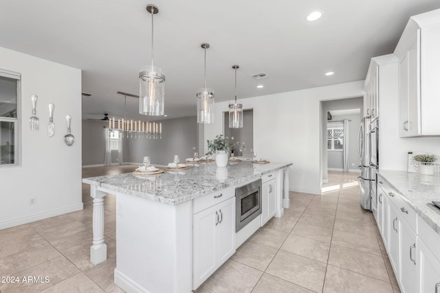 kitchen featuring pendant lighting, a center island, white cabinetry, and stainless steel microwave