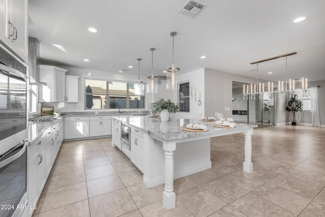 kitchen with a breakfast bar, a center island, white cabinets, and decorative light fixtures