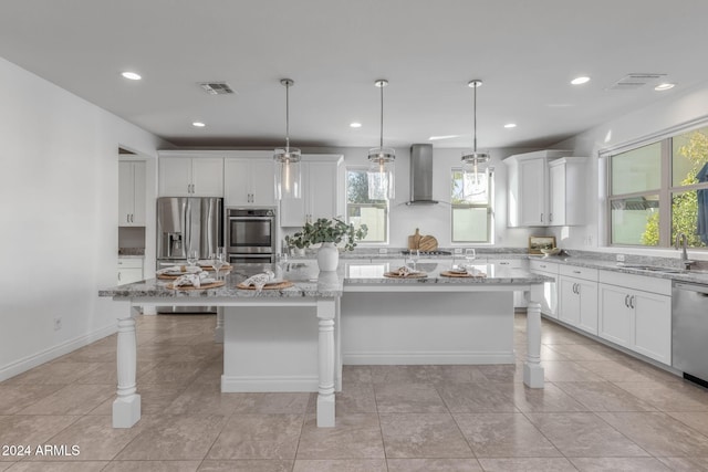 kitchen featuring sink, wall chimney exhaust hood, decorative light fixtures, a kitchen island, and stainless steel appliances