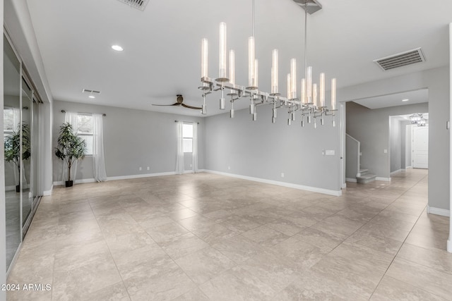 empty room with ceiling fan with notable chandelier