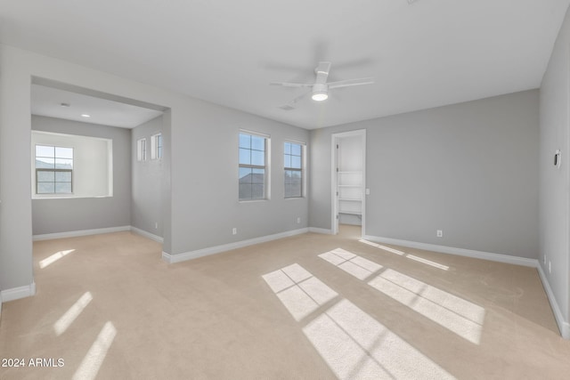 unfurnished room with light colored carpet and ceiling fan