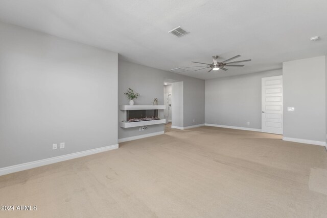 unfurnished living room with light colored carpet and ceiling fan