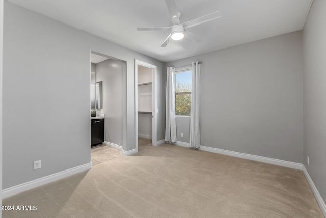 carpeted bedroom featuring ensuite bath, a spacious closet, a closet, and ceiling fan