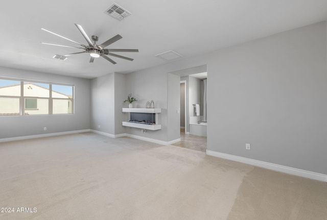 unfurnished living room featuring ceiling fan and light colored carpet