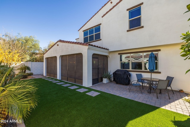 back of property with a lawn, a patio area, and a sunroom