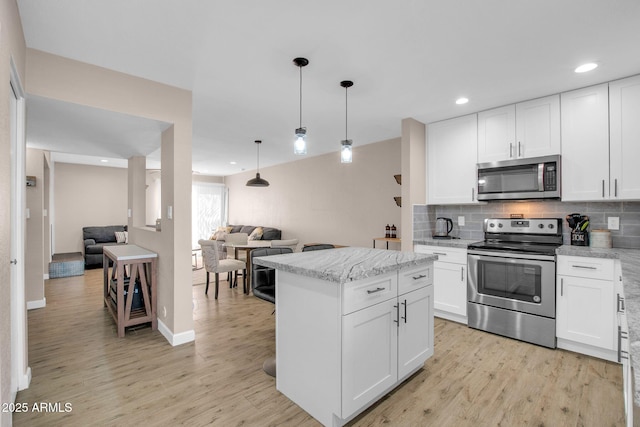 kitchen with stainless steel appliances, hanging light fixtures, a kitchen island, and white cabinets