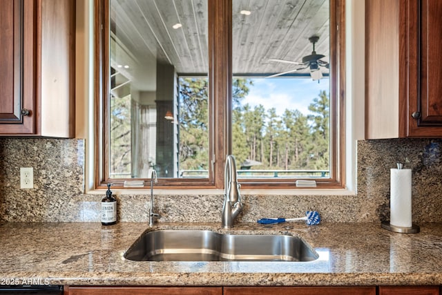 kitchen with tasteful backsplash, ceiling fan, light stone countertops, and sink