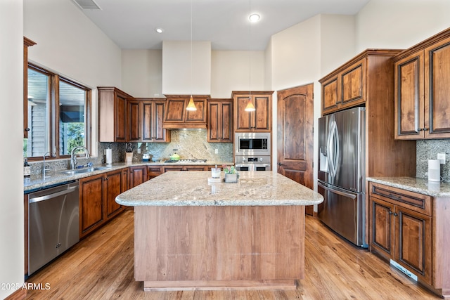 kitchen featuring a kitchen island, appliances with stainless steel finishes, sink, and light stone counters