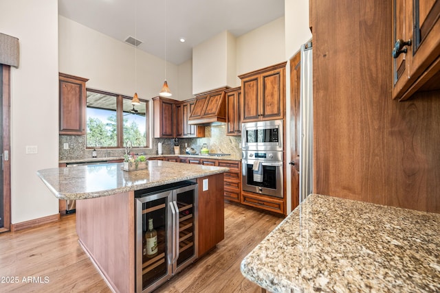 kitchen featuring appliances with stainless steel finishes, pendant lighting, wine cooler, a center island, and light stone countertops