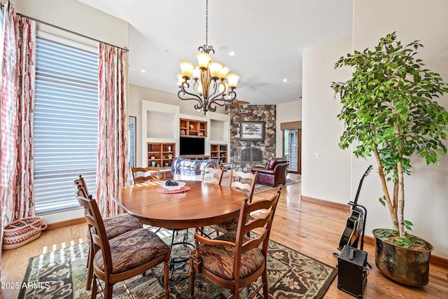 dining room with a stone fireplace, wood-type flooring, and a chandelier