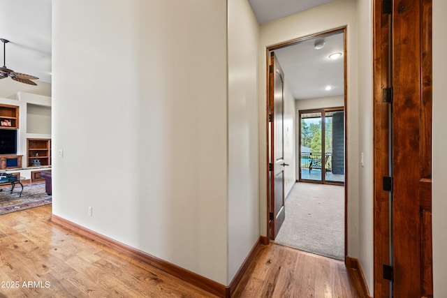 corridor featuring built in shelves and light hardwood / wood-style floors