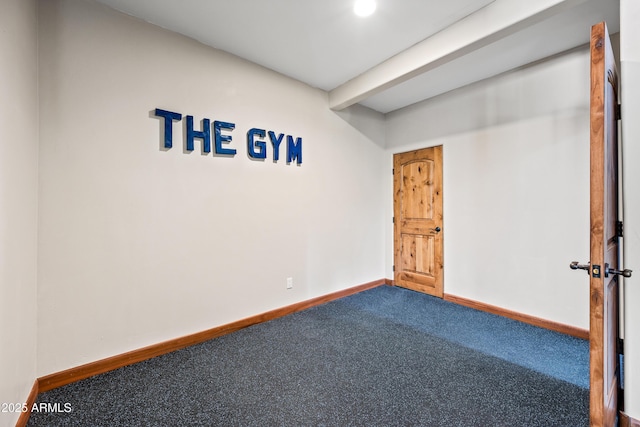 unfurnished room with beamed ceiling and carpet flooring