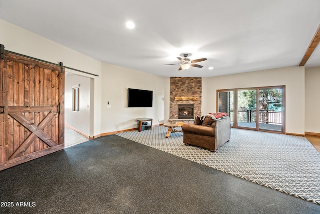 living room featuring ceiling fan, a barn door, carpet floors, and a fireplace