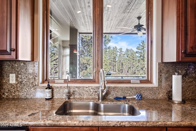 kitchen featuring ceiling fan, sink, decorative backsplash, and stone counters