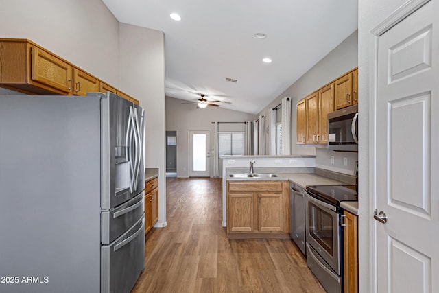 kitchen featuring a ceiling fan, appliances with stainless steel finishes, a peninsula, light wood finished floors, and lofted ceiling