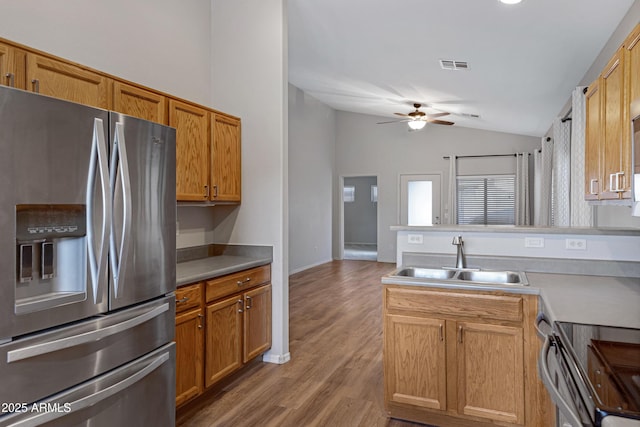 kitchen featuring a peninsula, ceiling fan, stainless steel refrigerator with ice dispenser, a sink, and vaulted ceiling