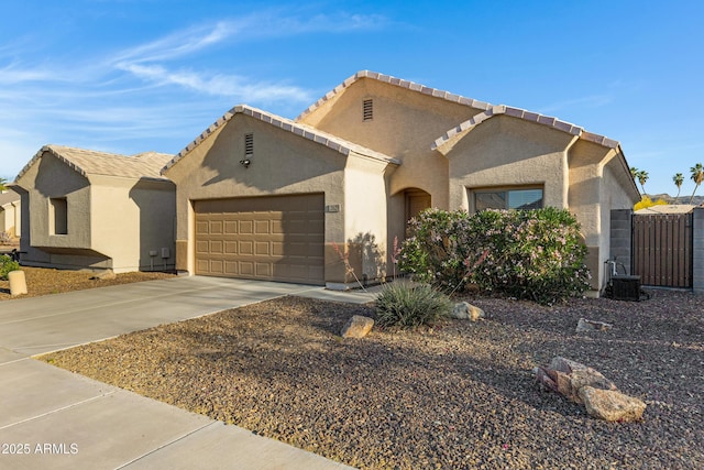 view of front of home with fence, an attached garage, stucco siding, concrete driveway, and central air condition unit